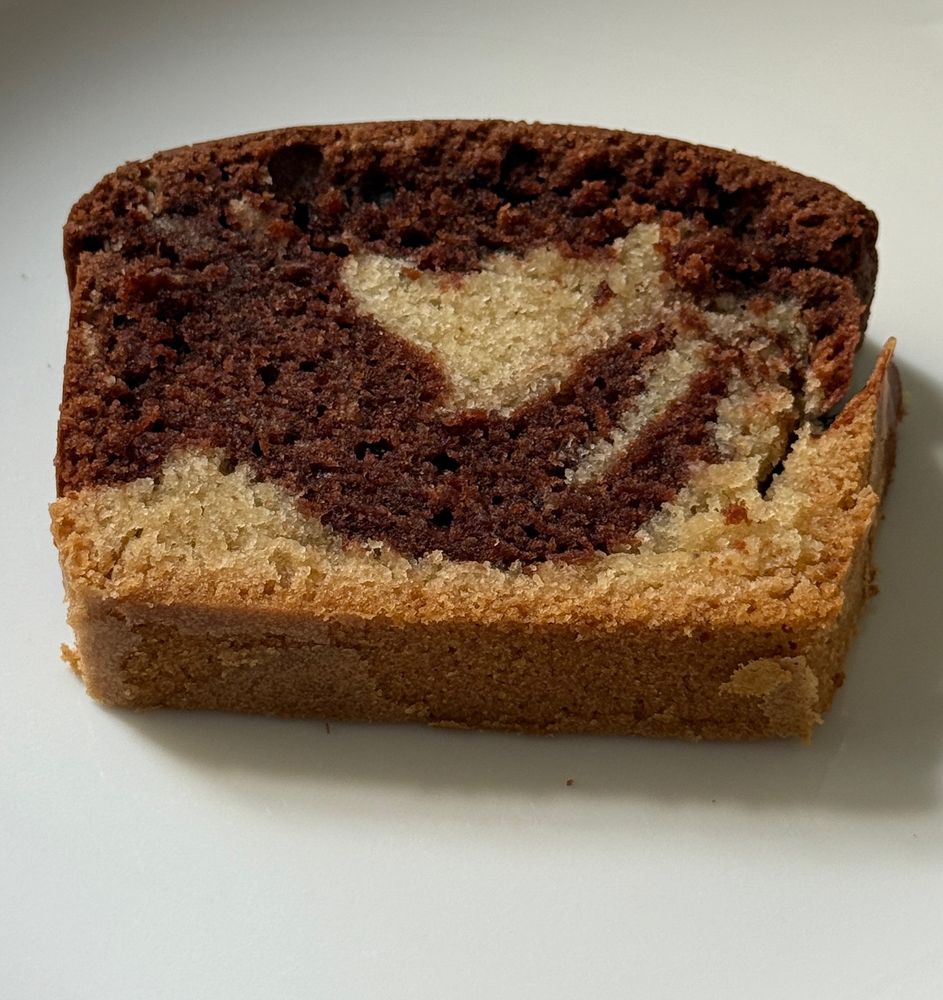 Eine Scheibe Mamorkuchen liegt auf einem weißen Porzellanteller