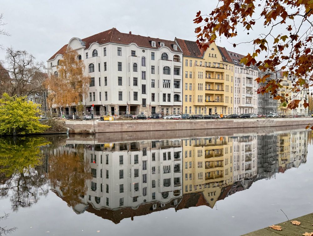 Foto einer Häuserfront, die sich im Wasser spiegelt. 