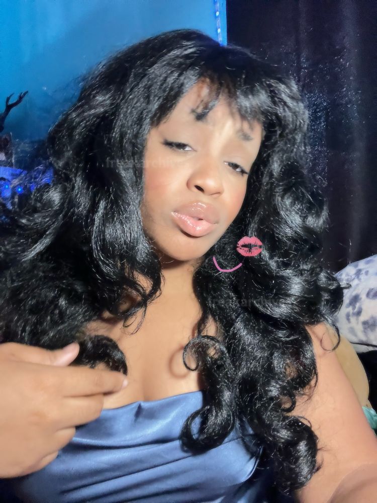 myself with black hair and loose curls, with a satin blue romper on as well. i have edited in a kiss mark with a pink line showing i’m blowing you a little smooch!