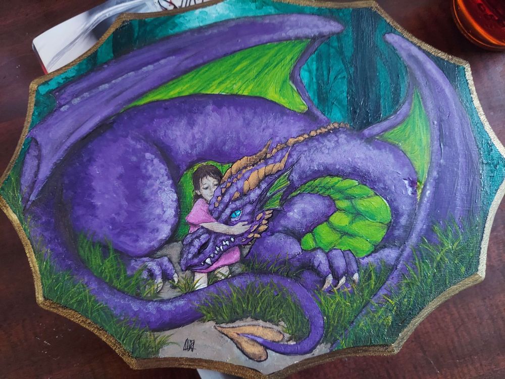 A full painting done on a plaque made of wood. The painting depicts a large green, purple and orange dragon curled protectively around a small child. The child is holding the dragon's large head in an embrace. They sit in soft yellow green grass, in the midst of a blue-green background of trees. 