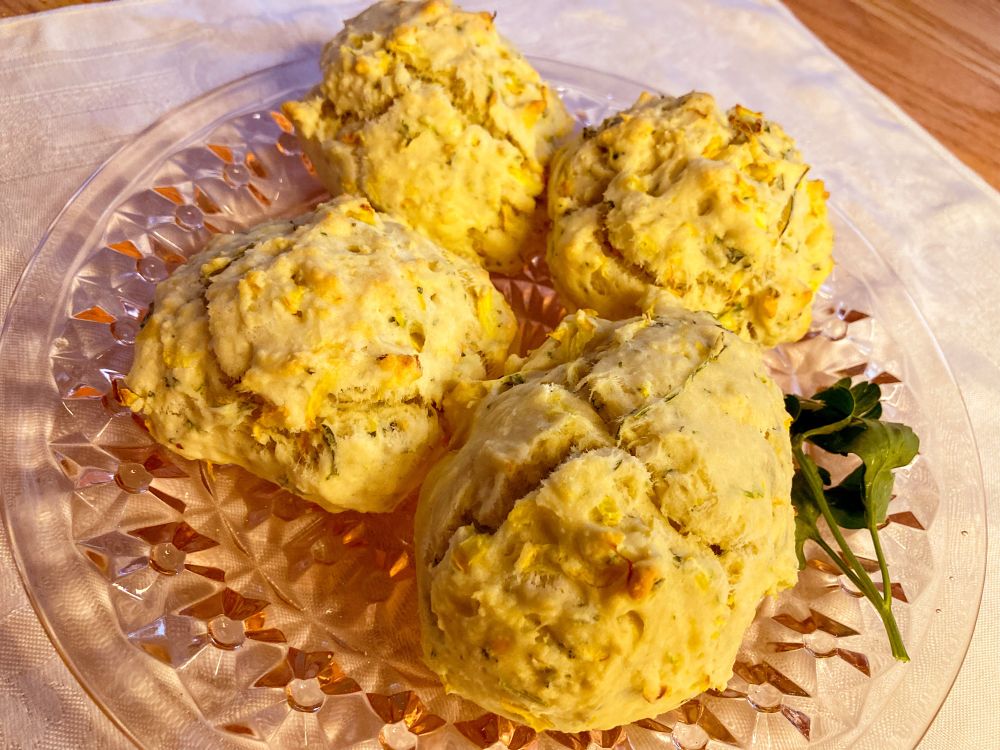 Four yellow squash and herb scones sit on a beautiful antique pink uranium glass plate