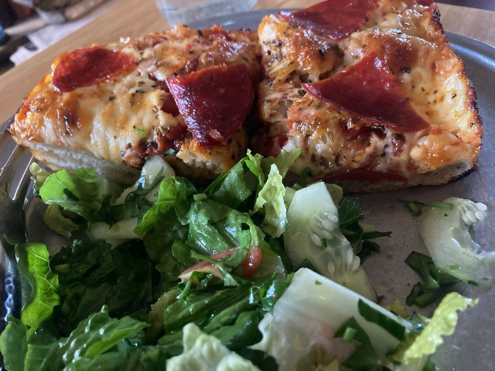 Thick slices of pan style pizza with pepperoni and a green salad on the side 