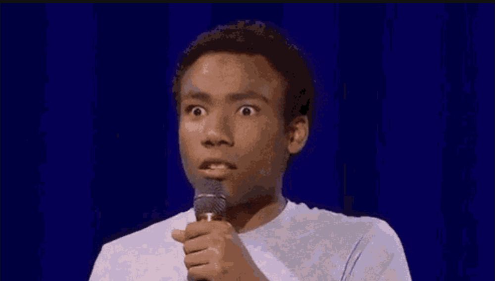Donald Glover holding a microphone staring intensely with wide eyes.