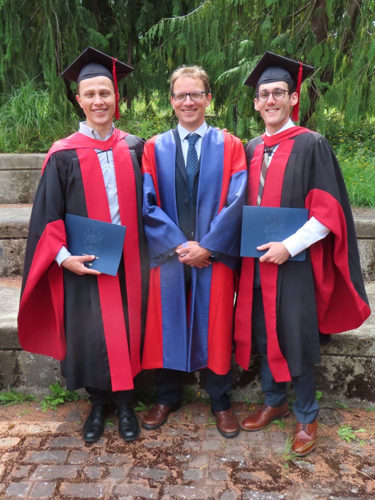 three people dressed in PhD regalia