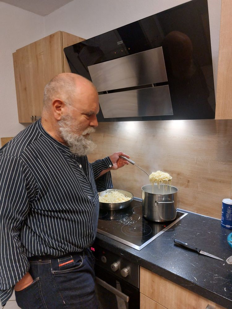 Ich stehe in der Küche am Herd und seihe mit dem Schaumlöffel Spätzle ab.