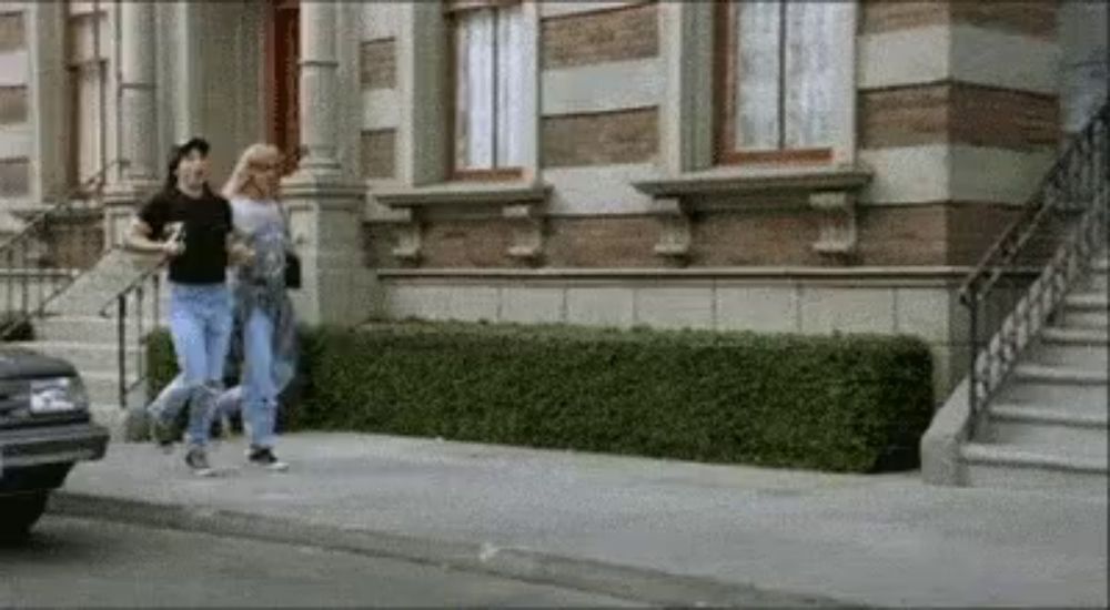 a man and woman are walking down a sidewalk in front of a building .