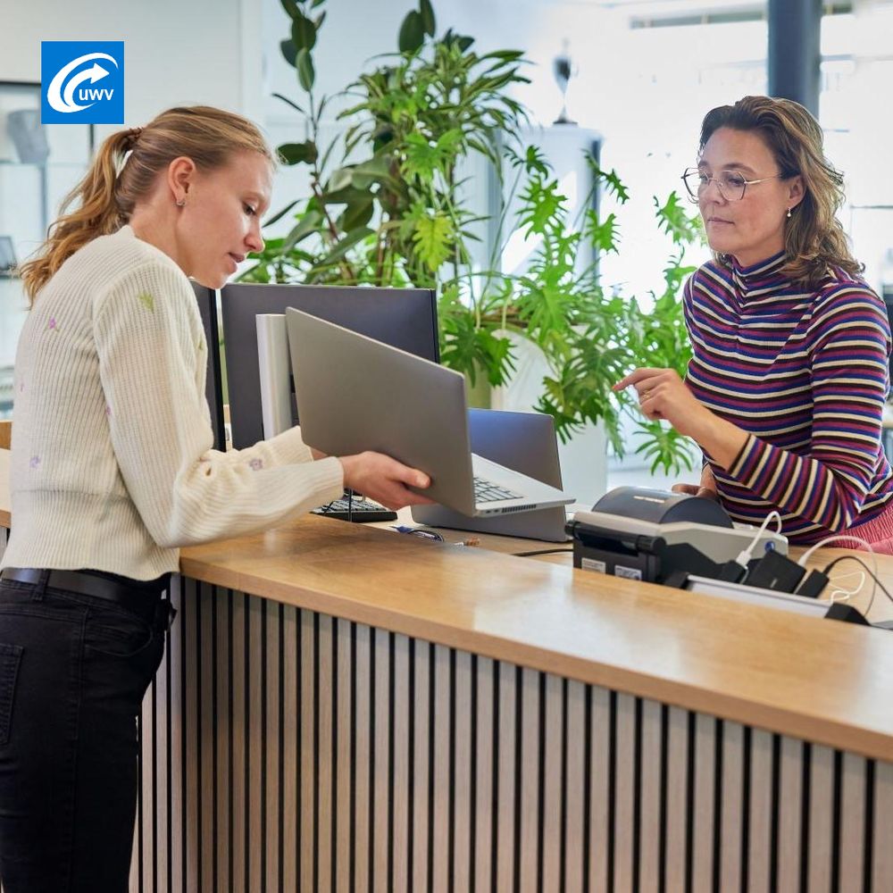 Een vrouw laat bij een balie het scherm van haar laptop zien aan een andere vrouw