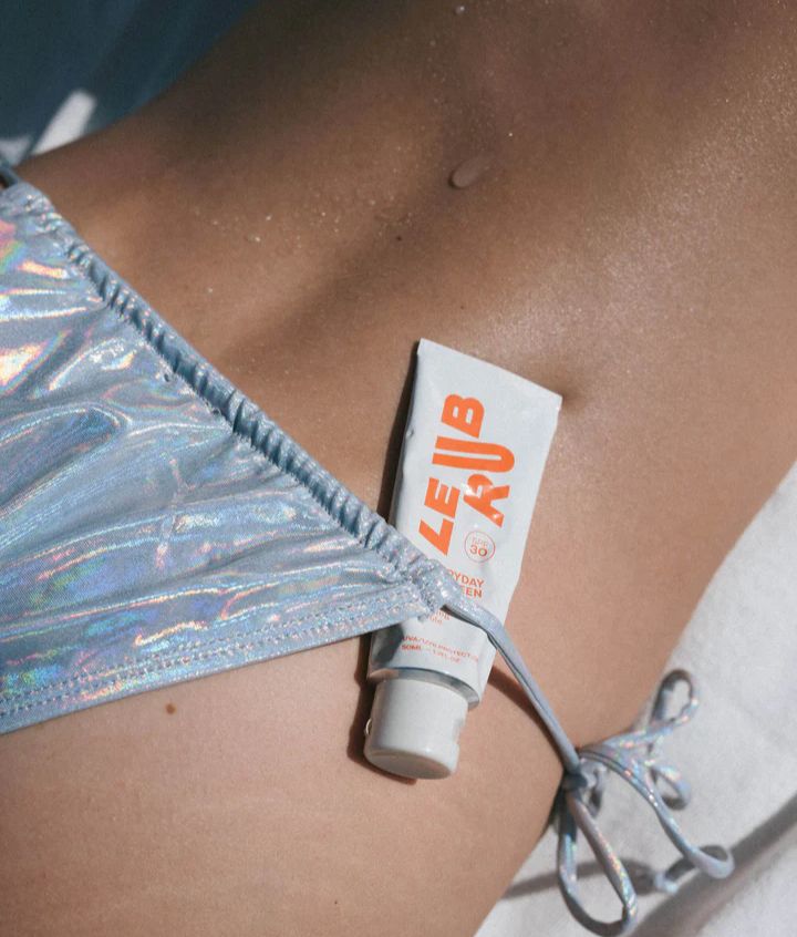 Zoom sur une crème solaire glissé dans le maillot de bain de la dame. 
