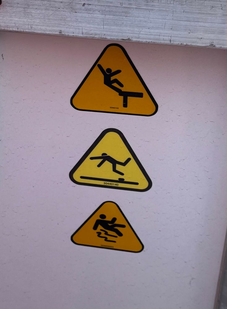 The three warning signs on the stairs up to an aircraft. 