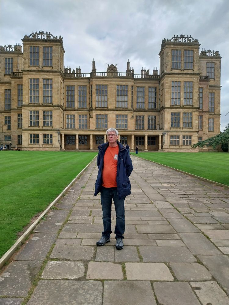 Eluzabethan house. Many windows. Man standing on oath.