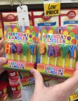 A picture of birthday candles in a grocery store. They spell out "HAPPY BAPPY".