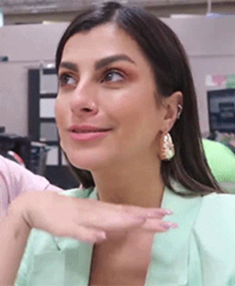 a woman wearing a green jacket and earrings is sitting in a chair .