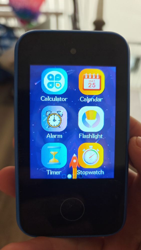 A child's play phone. The screen is lit up showing apps such as calculator, calendar, and alarm