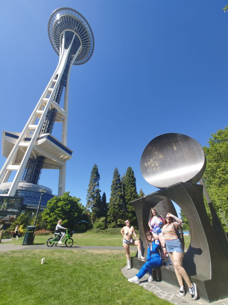 Friends standing in a piece of art in front of the Seattle Space Needle
