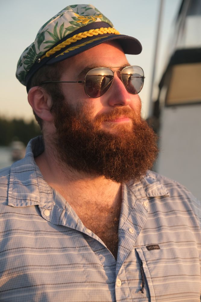 Captain Sugarman looks out to see at golden hour, the sun set reflected in his sunglasses