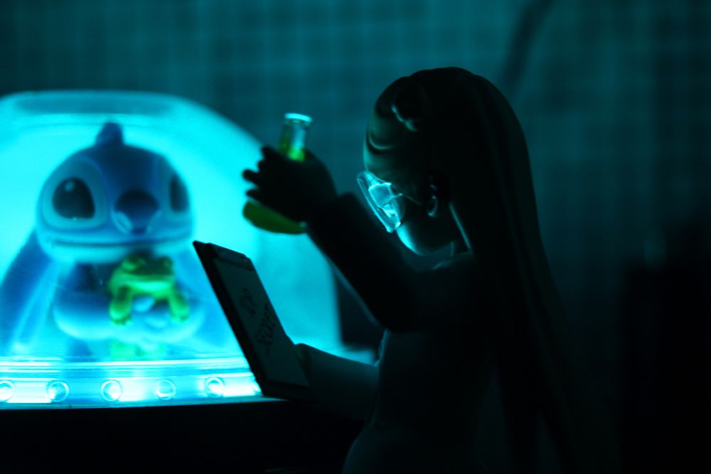 Scientist Poppy from Peach Riot looking at Disney's Stitch. Stitch is standing inside a glass dome. The scene is a lab and is illuminated with blue light coming from Stitch's capsule.
