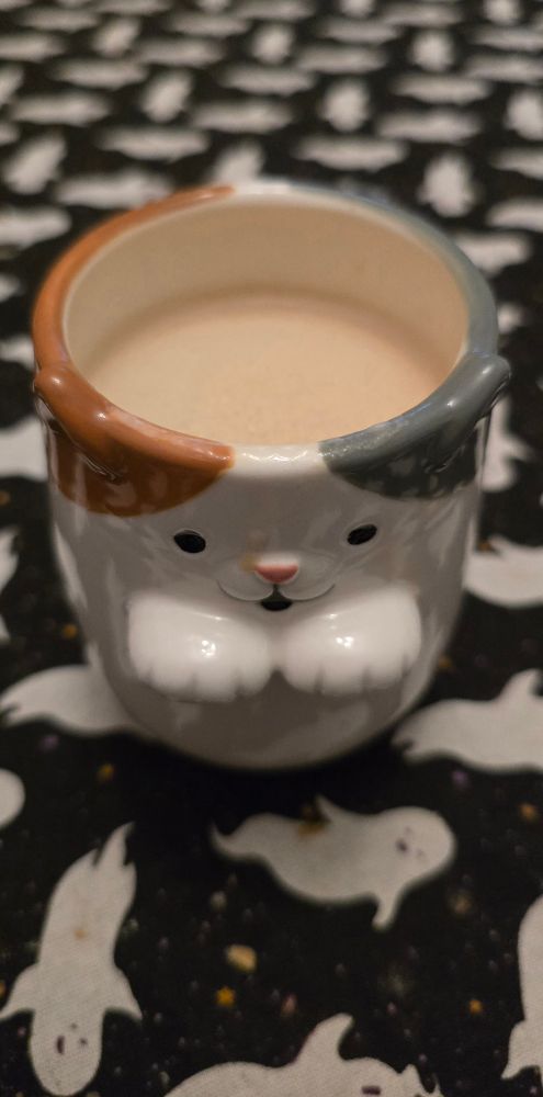 Kaffee in Katzentasse auf Geistertischdecke