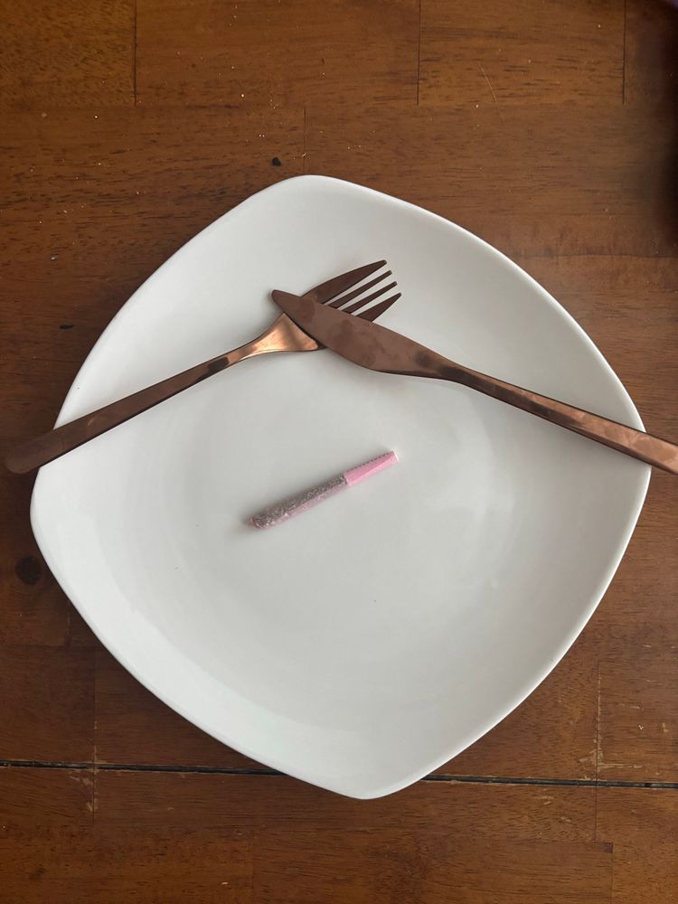 a white plate with coppery silverware and a slim pink joint on the plate for breakfast 