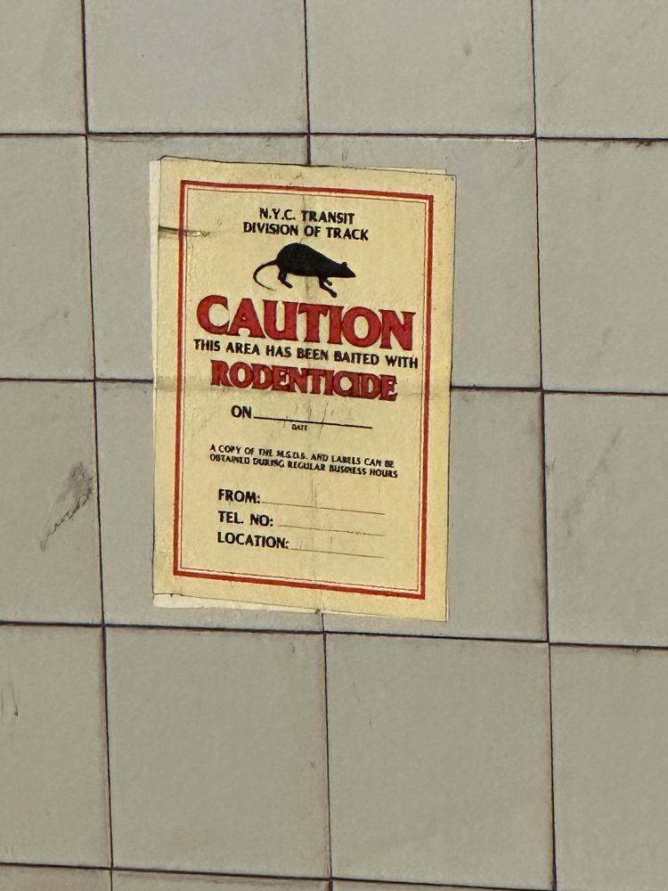 A caution poster saying there is rodenticide on New York City train tracks. There is a silhouette of a rat and red text saying caution. 