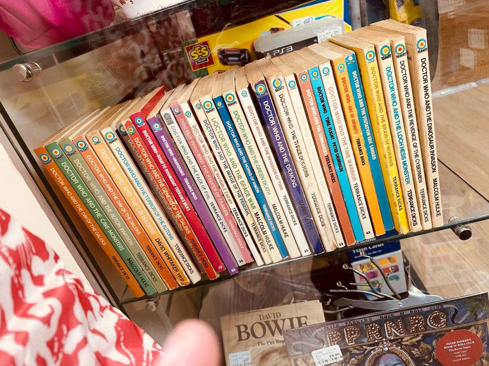 A row of Target DOCTOR WHO paperbacks inna display cabinet.