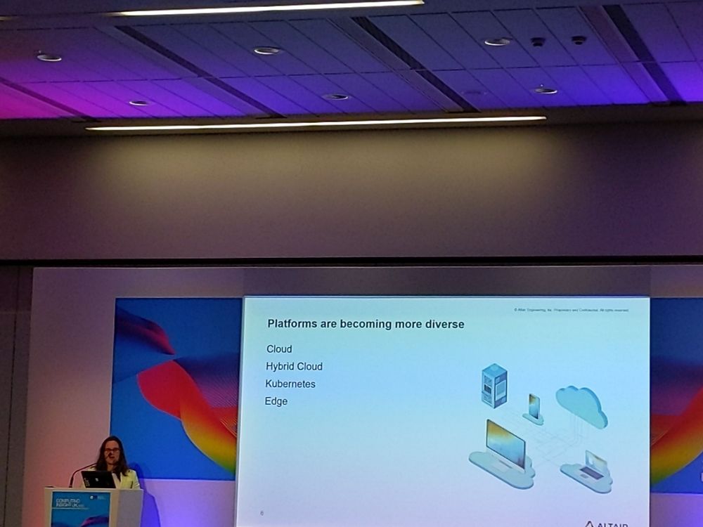 woman at lectern on left with slide projected large on right between CIUK logos