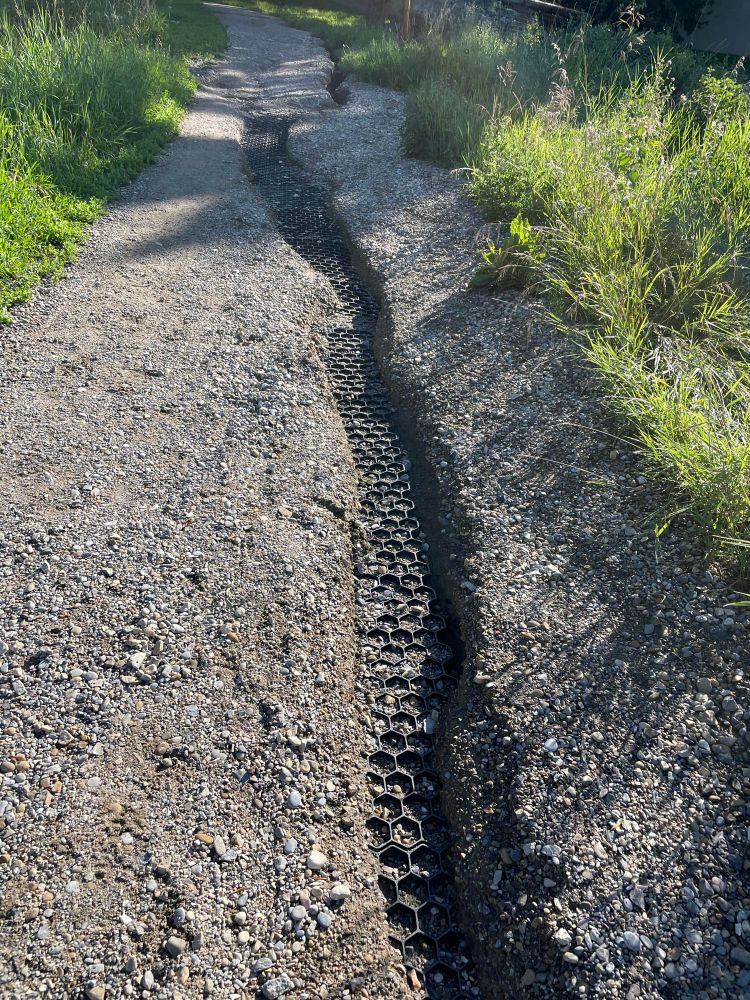 Photo of a walking path with a deep crevice showing the plastic Geo-grid underneath.