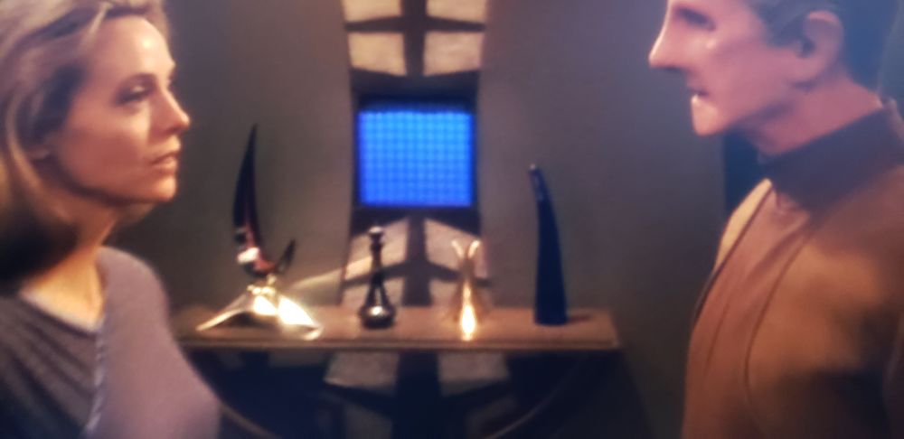 two characters standing in front of each other, about to kiss. props in the background could be considered stand ins for a boner and the whatever theyre saying with a crescent moon prop