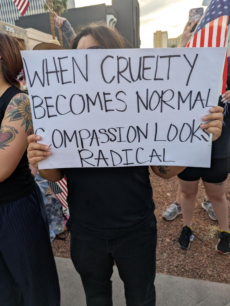 Protest sign says when cruelty becomes normal compassion looks radical
