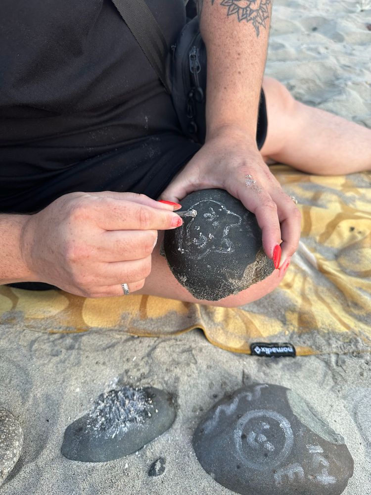 Katie using shells to grind white pigment to draw with 