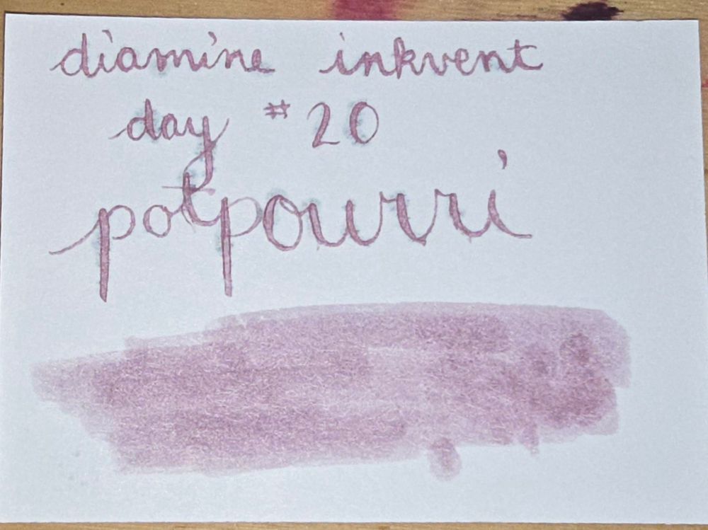 A swatch card that reads Diamine inkvent day 20 potpourri.  The swatch is a lavendar shade. There's some bleeding throughout the writing in several places.