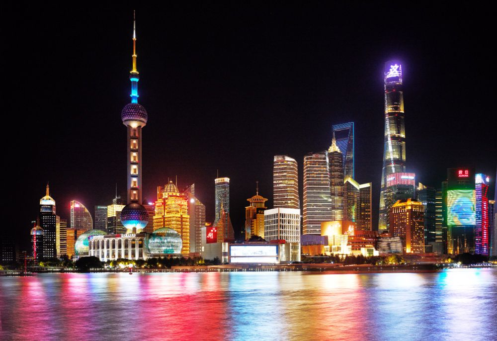 Shanghai skyline at night seen from the Bund, with bright neon lights reflecting across the river. Photo taken with a 6-second exposure just before the city lights were switched off. The photographer intended to capture stars, but the mix of light and air pollution made them invisible against the glowing skyline.