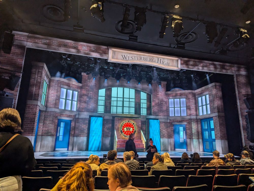 A theater stage decorated to look like a school hallway, with the name Westerberg High on the proscenium arch. 