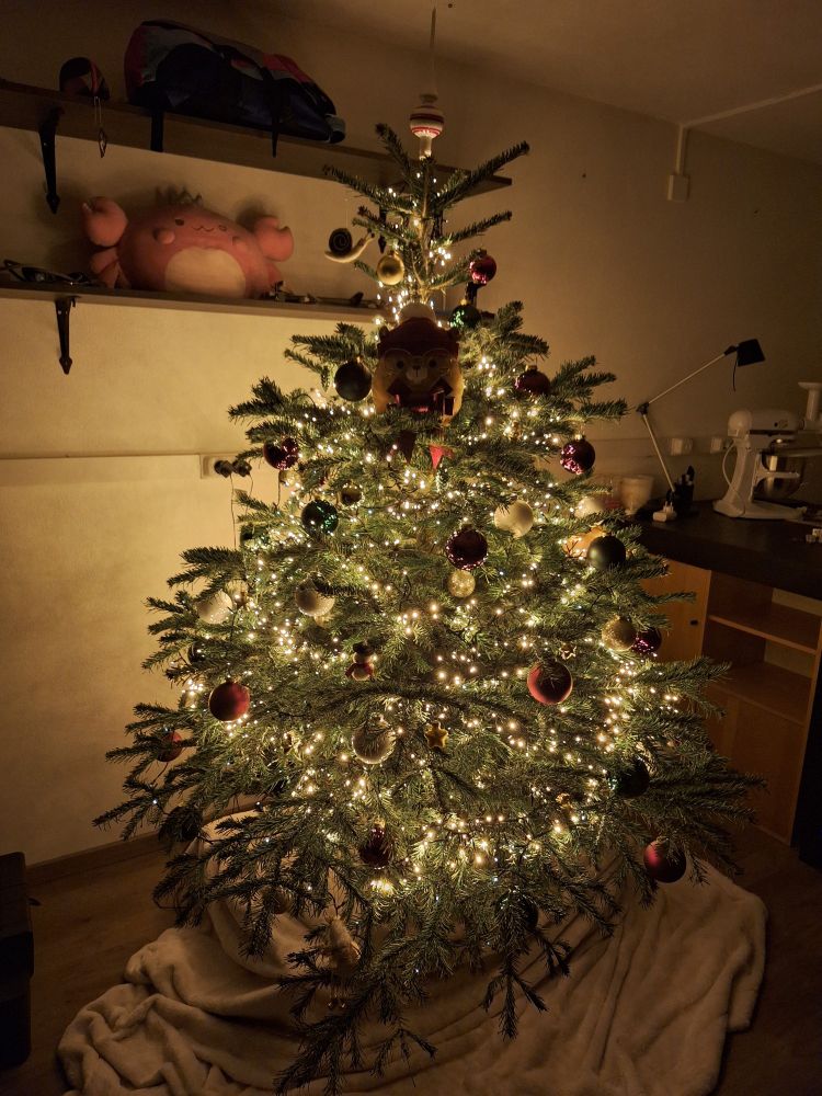 picture of a christmas tree decorated with yellow and white lights, balls of varying colours, ornaments, and a dapper looking fish!