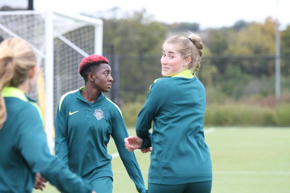 Spirit player Heather Stainbrook looks back with a smile starting to form. Behind her and to the left of the photo is teammate Deb Abiodun, looking off to the right of the photo