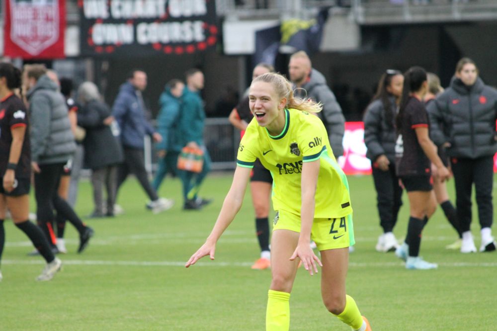 Esme Morgan, visibly excited, running toward the supporters section with a smile, bending forward and her hands out in front of her