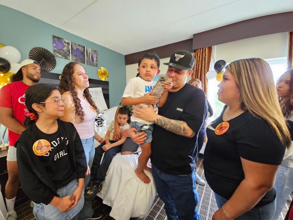 A zoomed out shot showing Kilmar Abrego Garcia in a Chicago Bulls hat that looks like the exact same one from one of the common photos of him. Other members of his family are visible to his right.