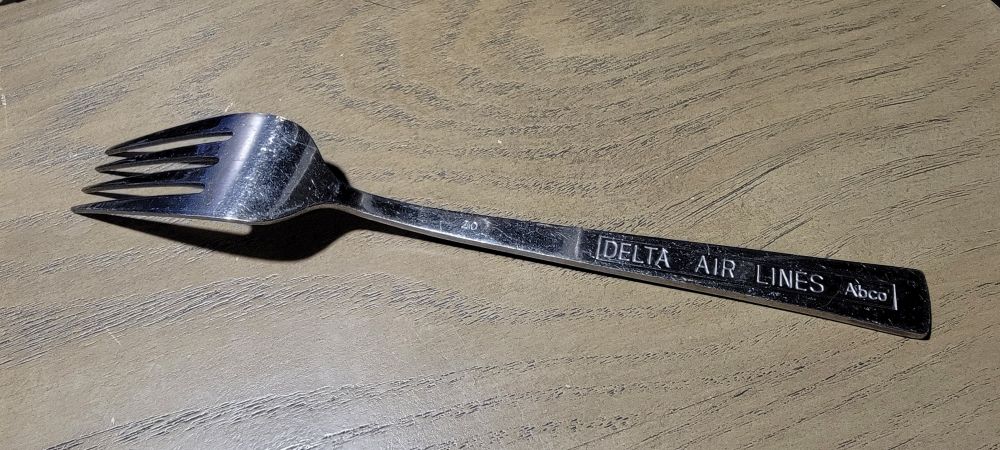The same fork flipped to its reverse side, showing a "DELTA AIR LINES Abco" stamp in a rectangle on the handle