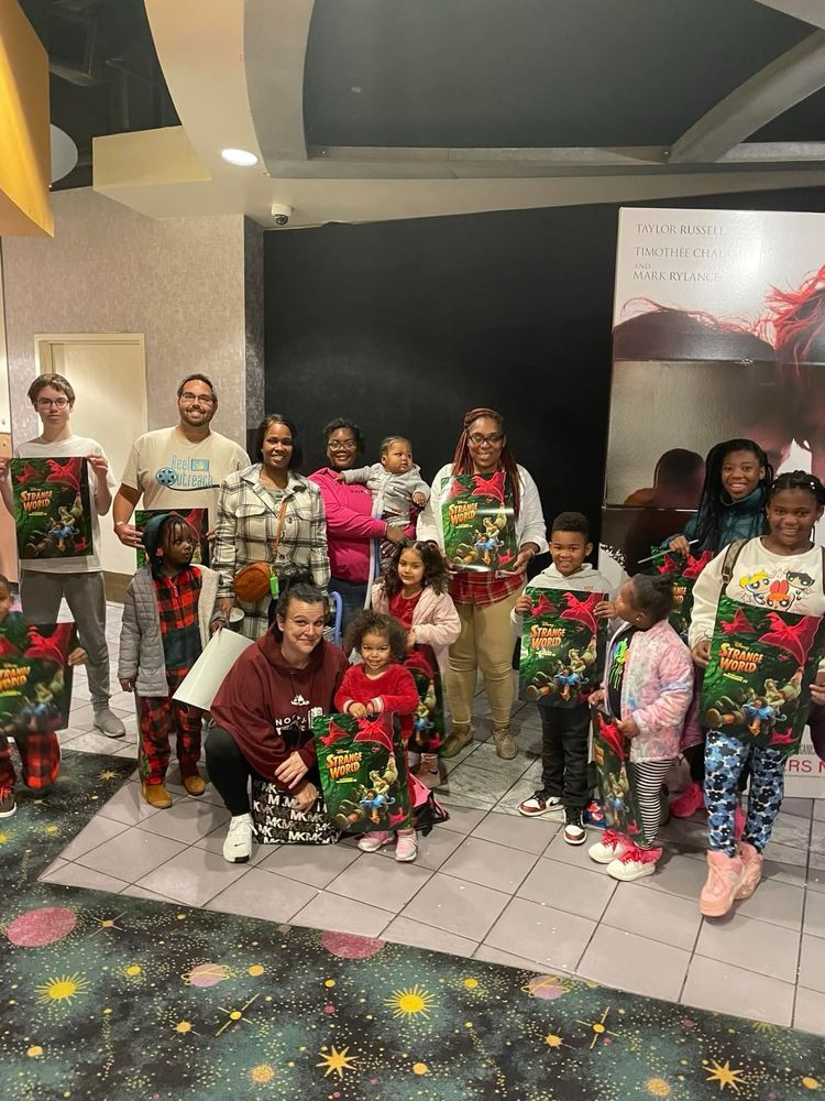 A bunch of people in front of a theater holding Strange World posters