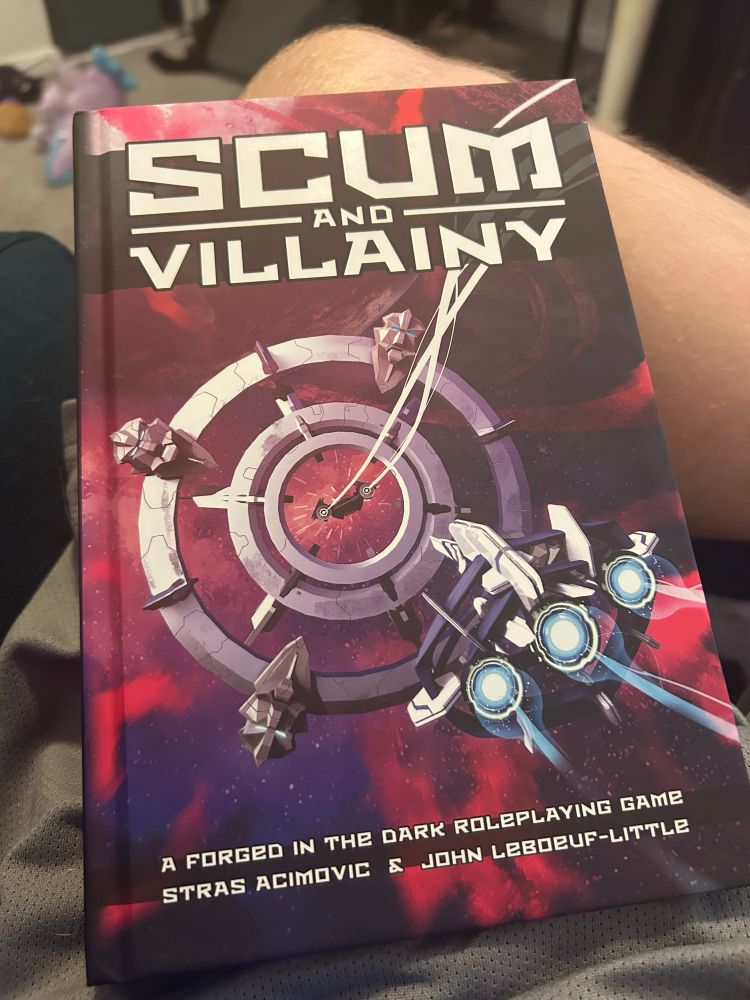 A hardback book called Scum and Villainy, a Forged in the Dark Roleplaying Game by Stras Acimovic and John Lebouef-Little