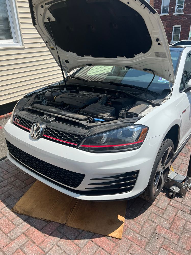A Volkswagen GTI lifted on jack stands waiting for an oil change.