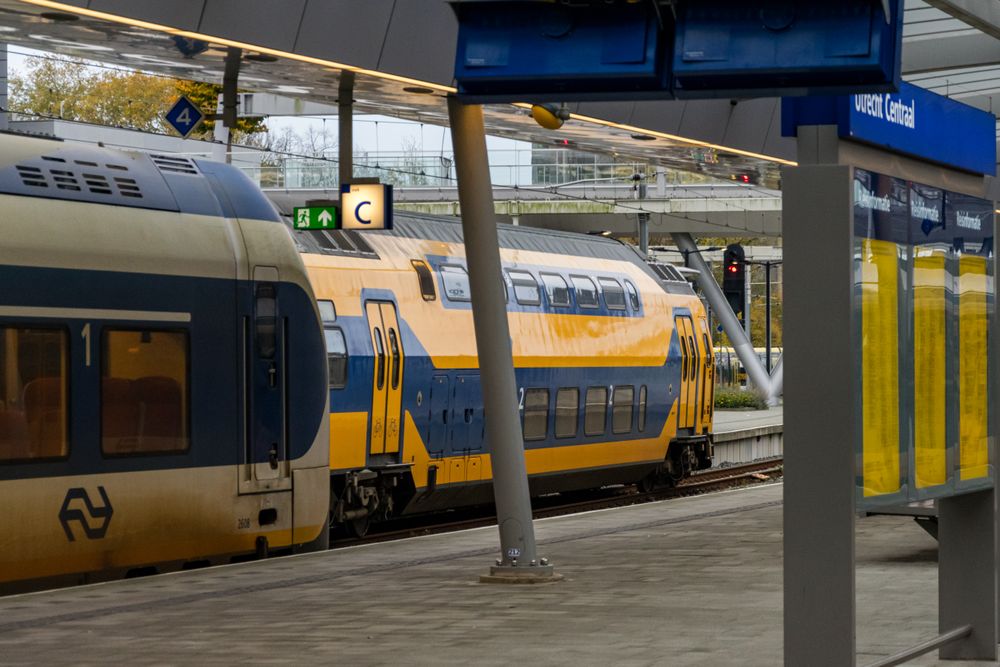 white-blue and yellow-blue trains at a station