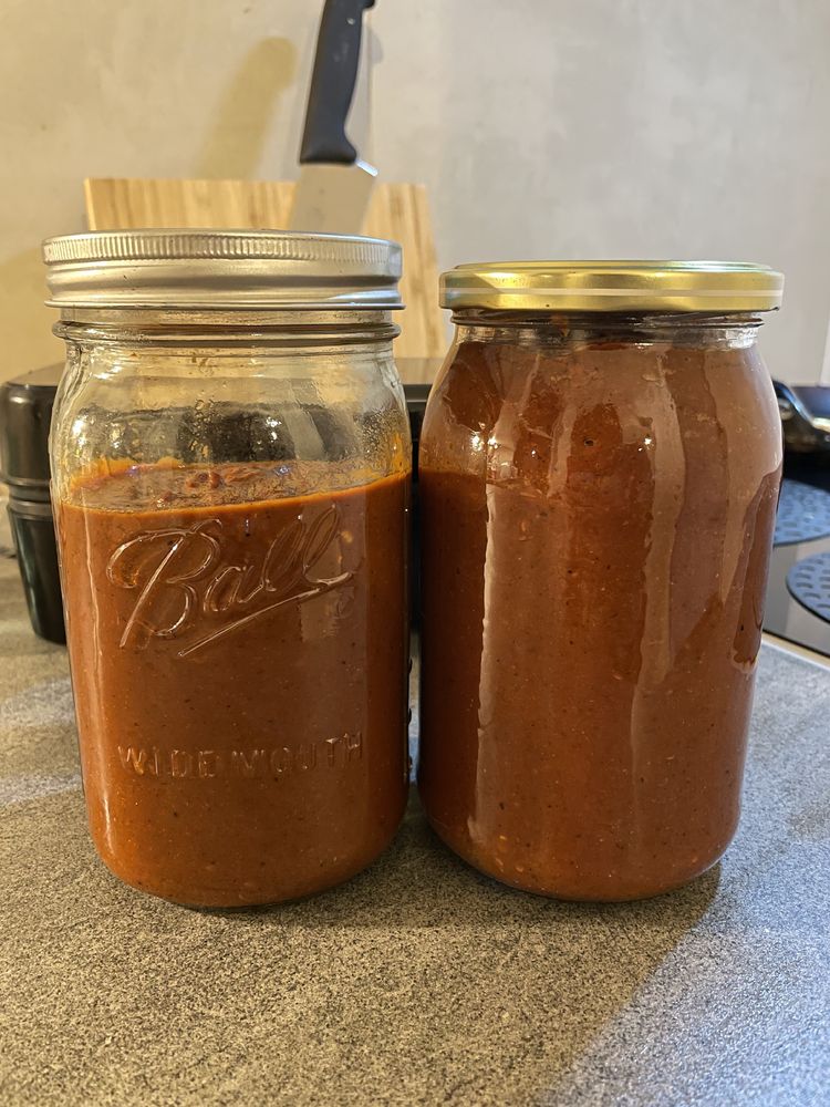 Two mason jars containing the resulting hot sauce. The sauce is dense and brown-ish 