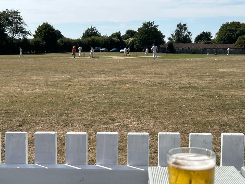 A sunny village cricket field with my pint of cider in frame