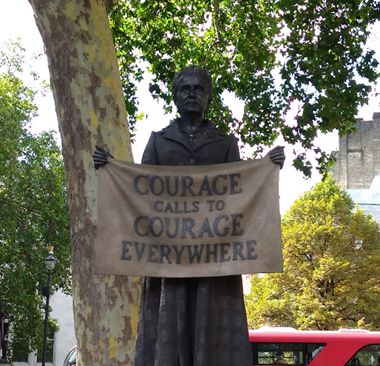 Statue of suffragette Millicent Fawcett in Parliament Square in London holding a banner with a slogan attribute to her that says 'Courage calls to courage everywhere'