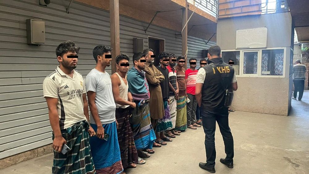 South Asian men lined up in front of a Kyrgyz security services officer 