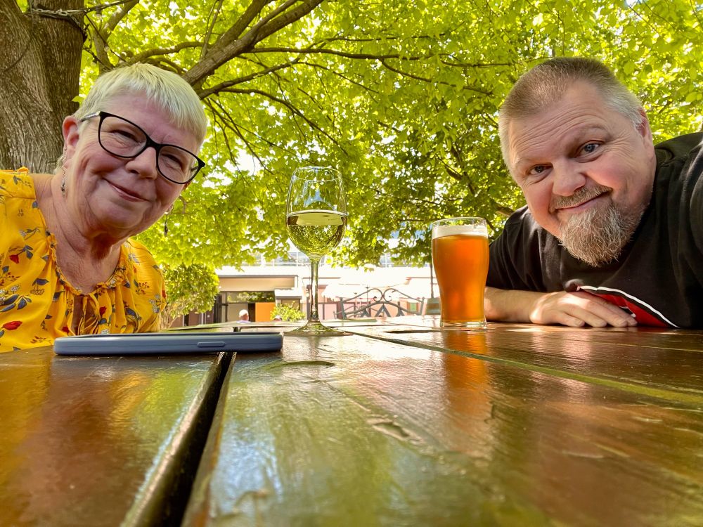 Dave and Jodi at a table outside at the pub under a beautiful green canopy of leaves