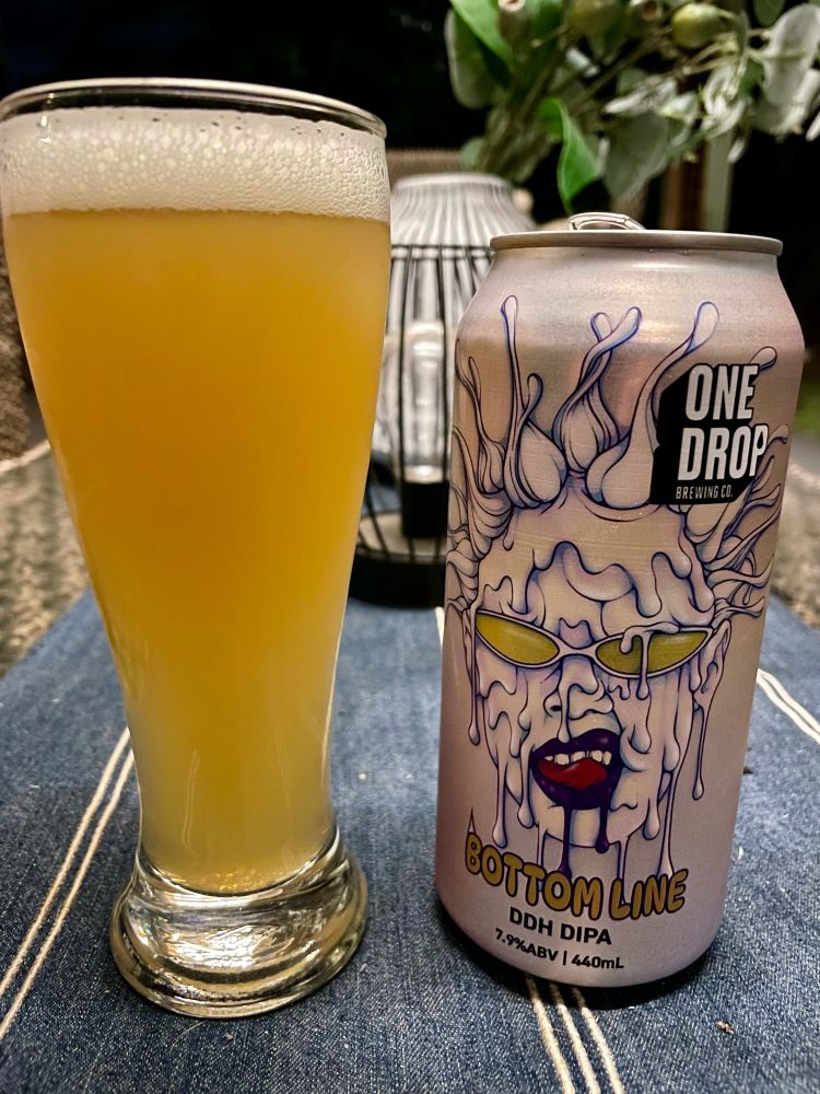 Tall glass of beer next to a silver can with a foaming face and sunglasses 