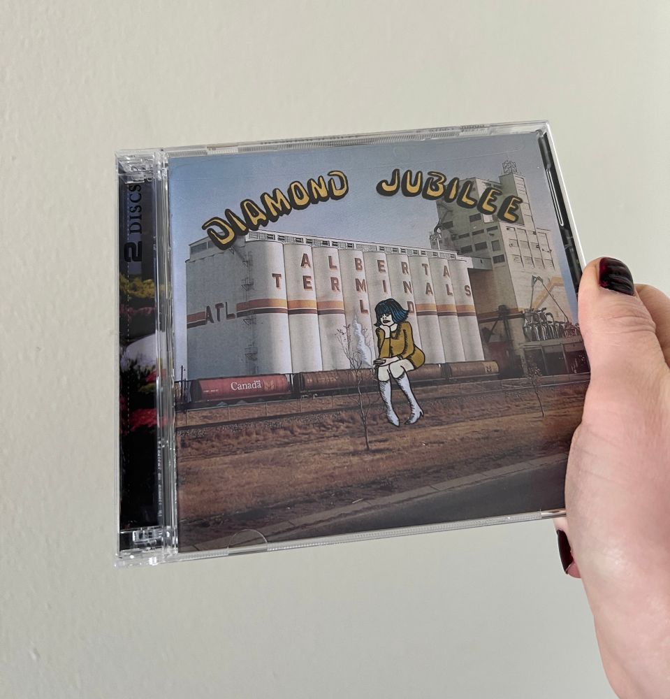 A white hand with red nail polish holding the new Cindy Lee album up in front of a white wall