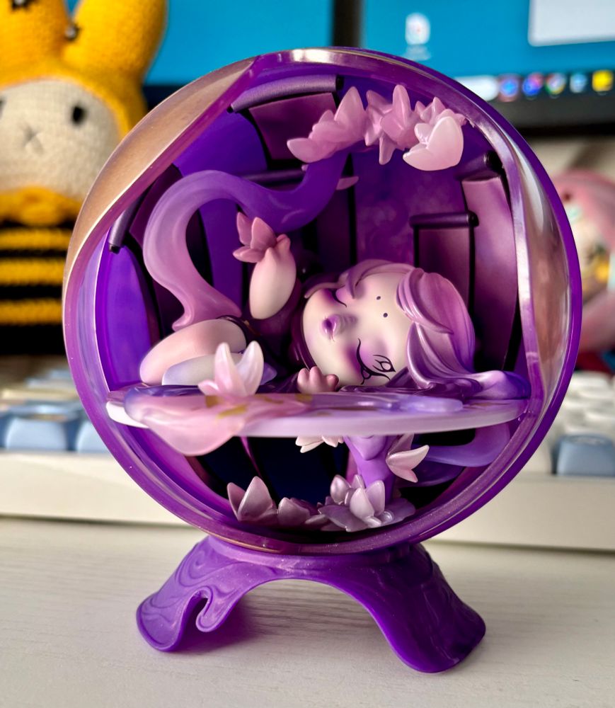 Skullpanda figurine The Butterfly. Purple orb with lavender and purple figurine laying on their side with butterflies 