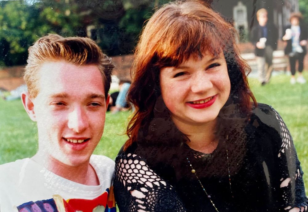 Reddish haired me in black spider web top sat next to my friend Duncan in a park. 